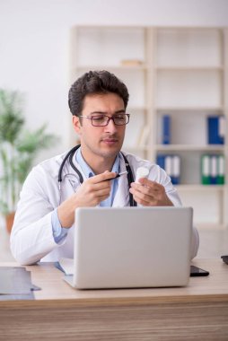Genç doktor hastanede hap öneriyor.