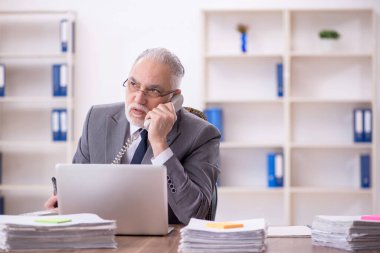Old businessman employee unhappy with excessive work at workplace