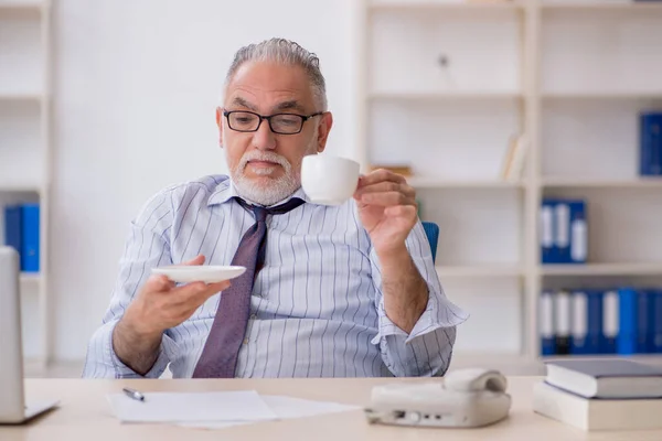 Old employee drinking coffee during break