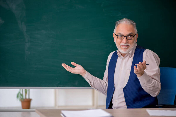 Старый учитель перед зеленой доской