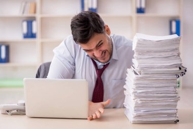 Young employee and too much work at workplace