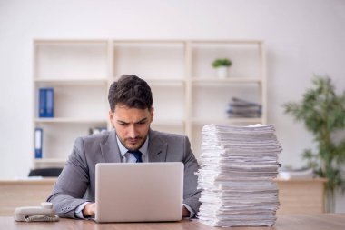 Young employee and too much work at workplace