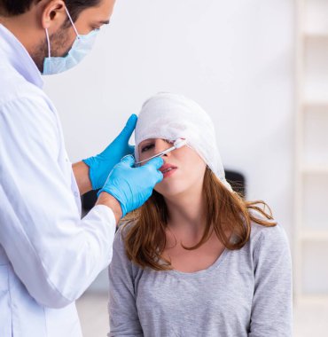 Genç yaralı kadın genç erkek doktoru ziyaret ediyor.