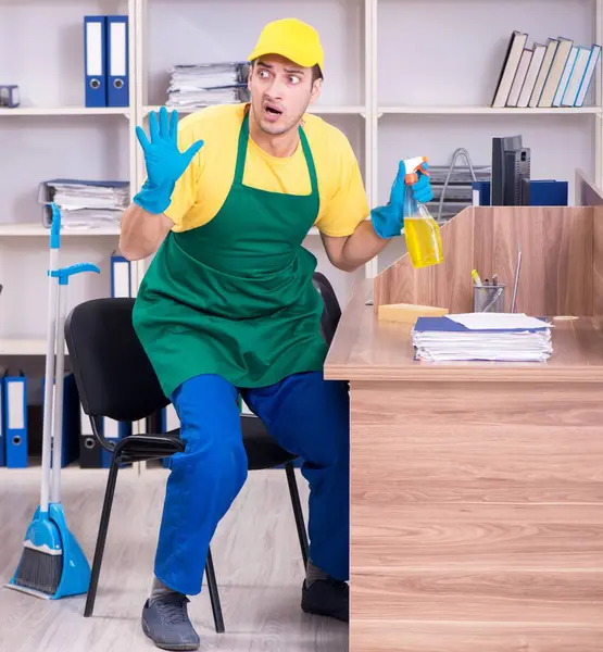 The young male contractor cleaning the office