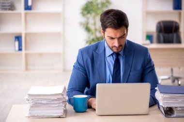 Genç işadamı ve işyerinde çok fazla iş var.