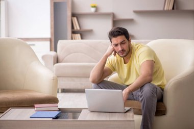 Genç erkek öğrenci salgın sırasında evden çalışıyor.