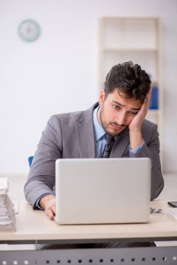 Genç bir çalışan ve ofiste çok fazla iş var.