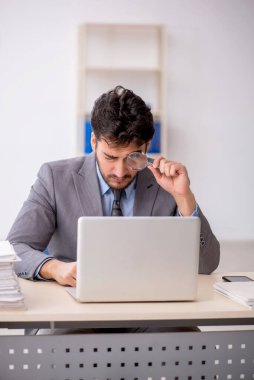 Genç bir çalışan ve ofiste çok fazla iş var.