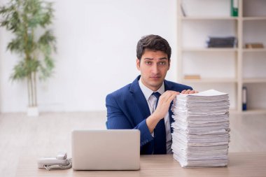 Young employee and too much work at workplace