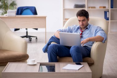 Genç işadamı işyerinde oturuyor.