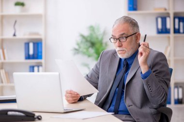 İş yerinde gazete okuyan eski bir çalışan.