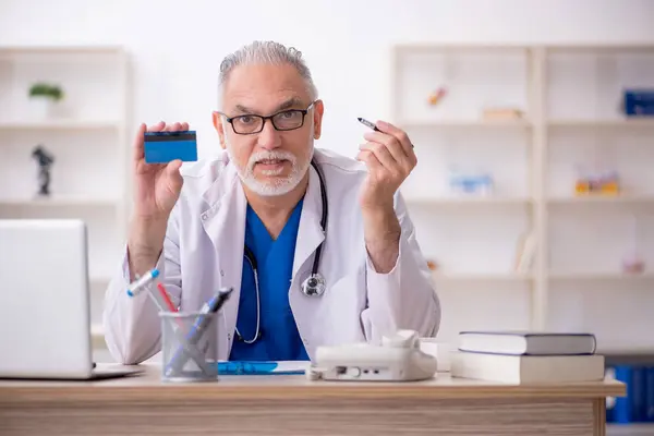 Old doctor holding credit card