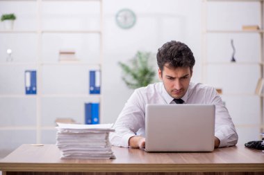 Young employee and too much work at workplace