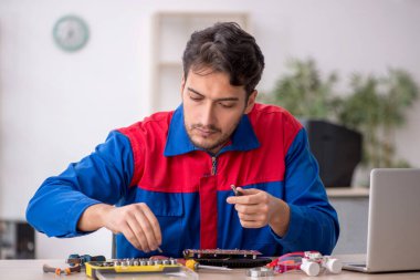 Laboratuvarda bilgisayar tamir eden genç bir tamirci.