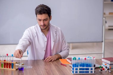 Young chemistry teacher sitting in the classroom