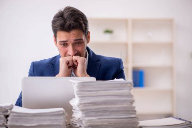 Young employee and too much work at workplace