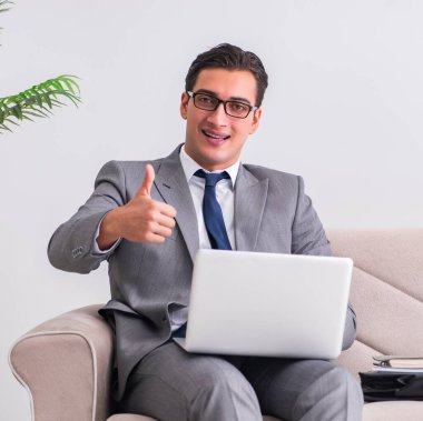 Dizüstü bilgisayarı olan iş adamı kanepede oturuyor.