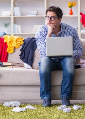 Dağınık odada çalışan genç adam.