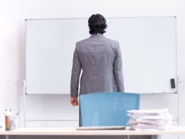 Genç yakışıklı iş adamı beyaz tahtanın önünde duruyor.