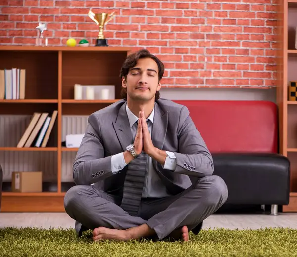 The young handsome employee doing yoga in the office