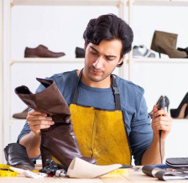 Atölyede ayakkabı tamir eden genç adam.