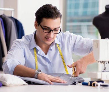 Genç terzi yeni elbiseler üzerinde çalışıyor.