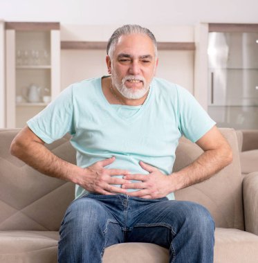 Beyaz sakallı yaşlı adam evde acı çekiyor.