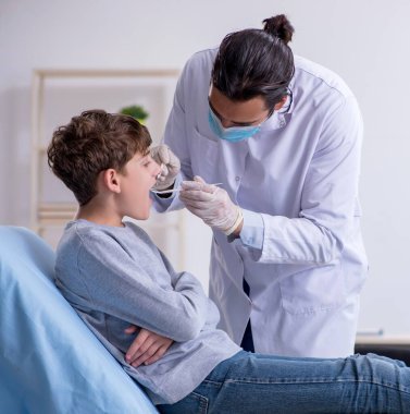 Genç çocuk hastanede doktoru ziyaret ediyor.