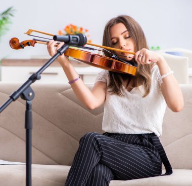 The female beautiful musician playing violin at home