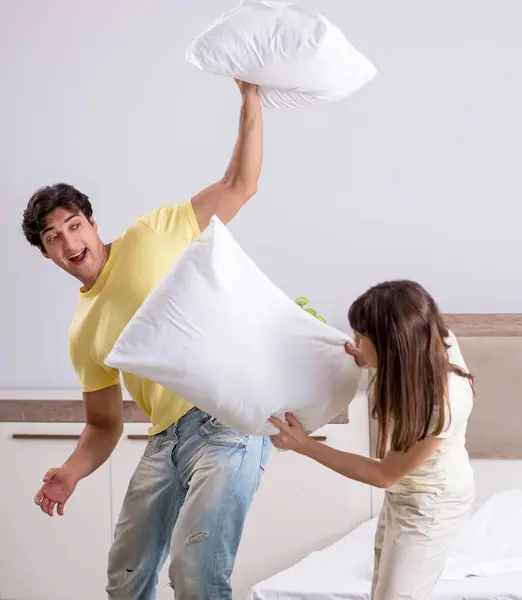 The wife and husband having pillow fight in bedroom