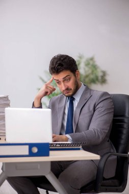 Young employee and too much work at workplace