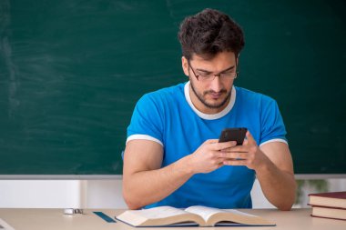 Sınıfta akıllı telefon tutan genç bir öğrenci.