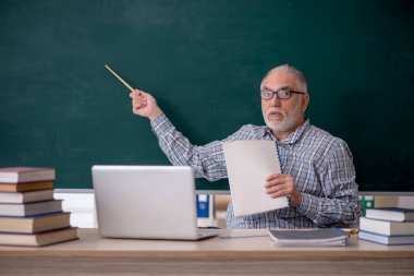 Old teacher sitting in the classroom