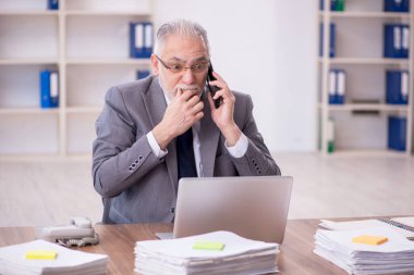 Old businessman employee unhappy with excessive work at workplace