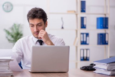 Young employee and too much work at workplace