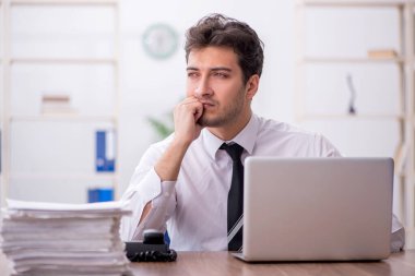 Young employee and too much work at workplace