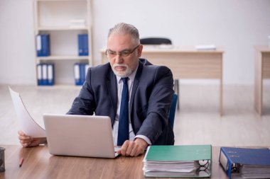 Old employee sitting at workplace