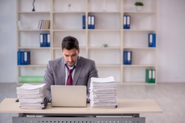 Young employee and too much work at workplace