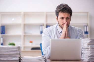 Young employee and too much work at workplace