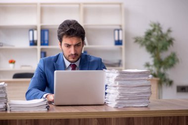 Young employee and too much work at workplace