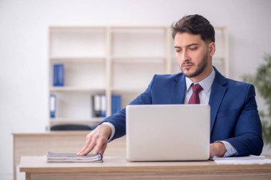 Genç işadamı işyerinde oturuyor.