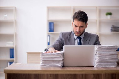 Young employee and too much work at workplace