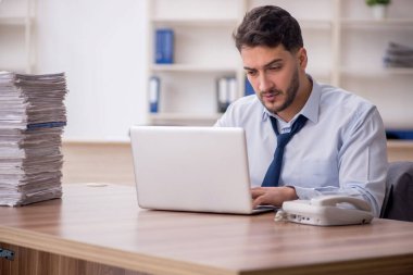 Young employee and too much work at workplace