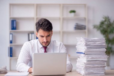 Young employee and too much work at workplace