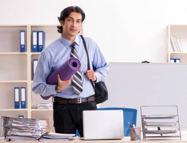 The young handsome male employee doing exercises in the office