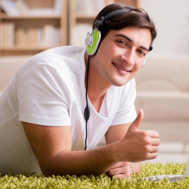Genç adam dizüstü bilgisayardan müzik dinliyor.