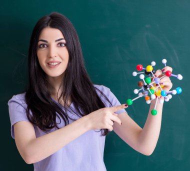 Yeşil panonun önündeki genç bayan öğretmen.