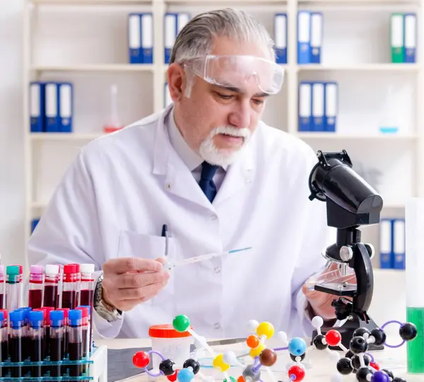The old male chemist working in the lab