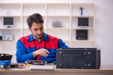 Atölyede bilgisayar tamir eden genç bir tamirci.