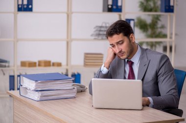 Genç işadamı işyerinde oturuyor.